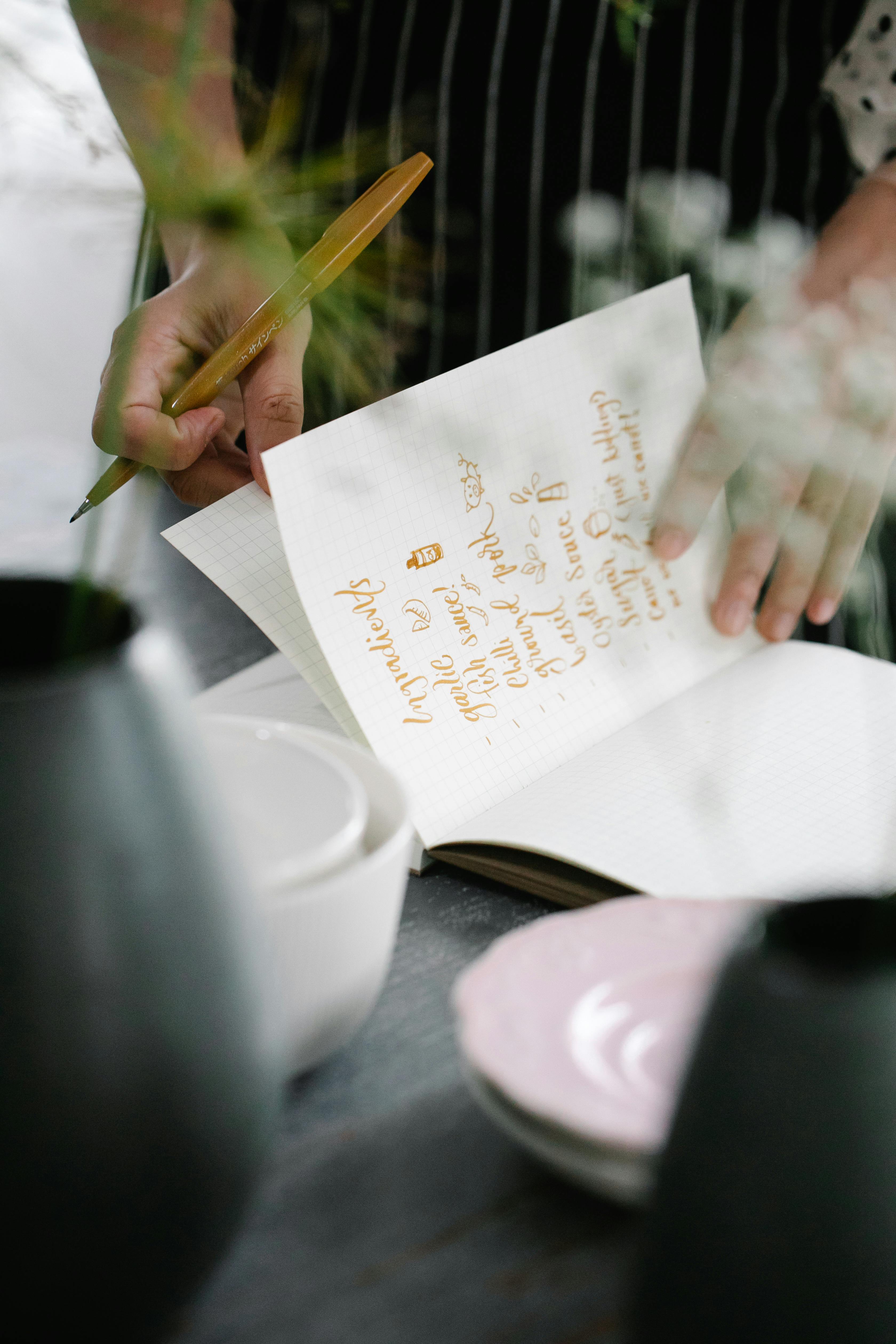 Chef writing in a cookbook at their kitchen counter